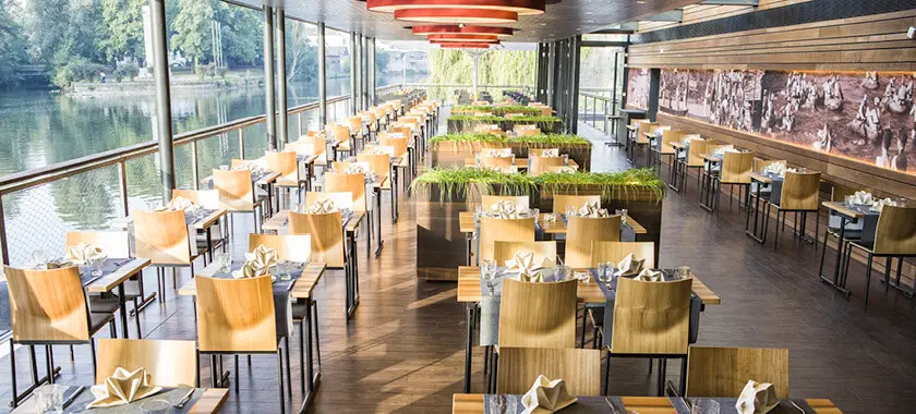 Gastraum des Bootshauses mit großer Glasfront und Blick auf das Wasser