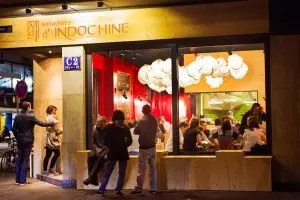 Außenansicht des Restaurants Indochine mit Holzfassade und Gästen vor der Türe