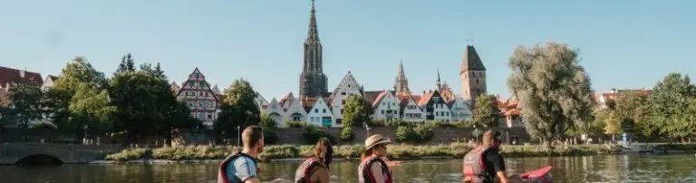 Gruppe von Kanufahrern auf der Donau vor der Ulmer Kulisse