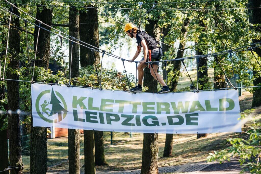 ein Mann klettert über ein Seil im Kletterwald Leipzig