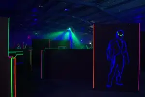 die Kulisse der LaserTag-Arena im Dunklen und mit Hindernissen, die durch Neon-Beleuchtung beleuchtet werden