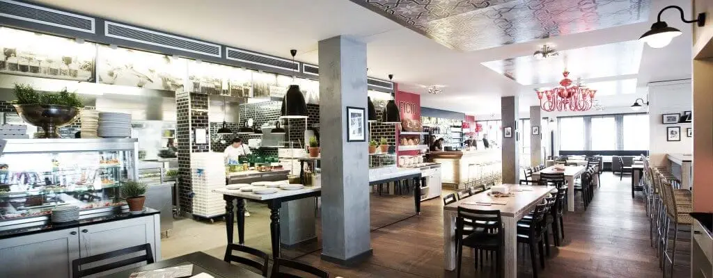 Innenraum der Losteria mit offener Küche und heller Architektur