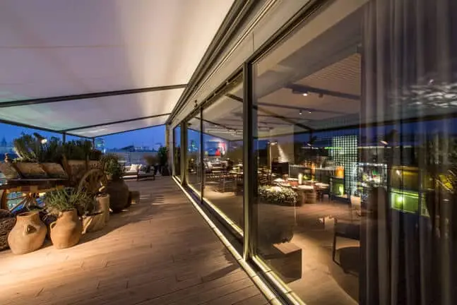 Dachterasse an einer großen Fensterfront mit Blick über Dächer im Hintergrund