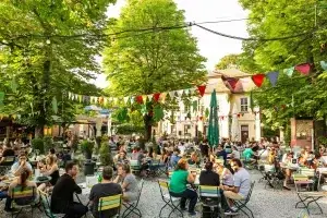 Innenhof des Talavera-schlösschen als Biergarten mit Sizmöglichkeiten und bunter Deko zwischen den Bäumen