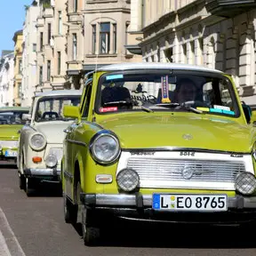 ein gelber Trabbi fährt auf einer Leizpiger Straße
