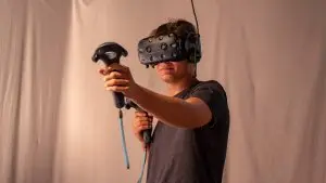 Mann, der eine VR Brille trägt und 2 Controller in der Hand hält
