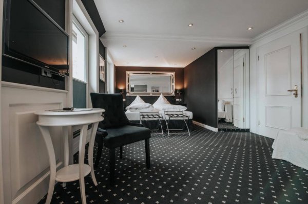 Blick in ein Doppelzimmer im Hotel "Rathaus" mit Doppelbett, Spiegelschrank und Sessel