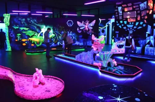 leuchtende UV-Farben an Wänden, Personen und Minigolfbahnen