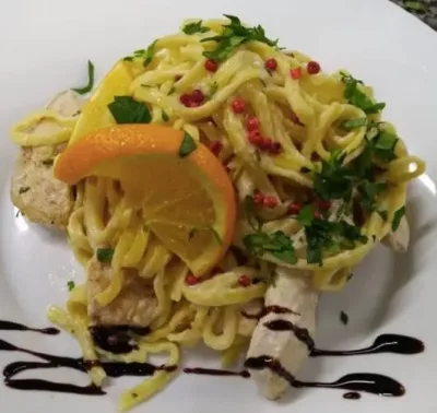 Zitronen-Hänchen mit Limonen-pasta angerichtet mit einer Scheibe Orange
