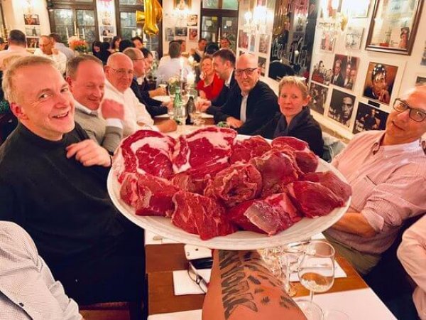 Eine Gruppe Personen hält einen Teller mit Steaks in die Kamera im Restaurant Una Volta